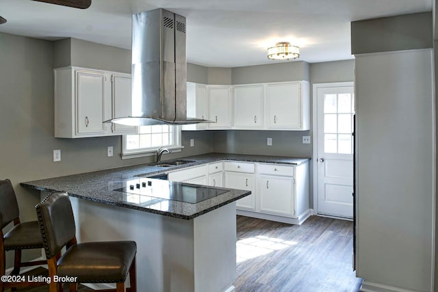 kitchen with black electric stovetop, sink, kitchen peninsula, and white cabinets