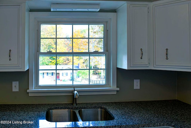 kitchen featuring white cabinetry, sink, and a wall unit AC