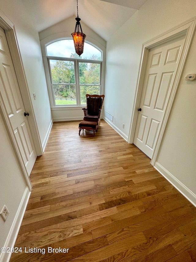 unfurnished room featuring lofted ceiling, a notable chandelier, and light hardwood / wood-style flooring