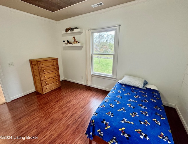 bedroom with ornamental molding and dark wood-type flooring