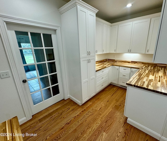 kitchen with white cabinets, wooden counters, and light hardwood / wood-style flooring