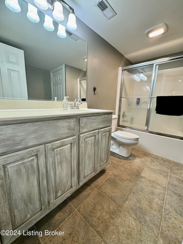 full bathroom with vanity, enclosed tub / shower combo, and toilet