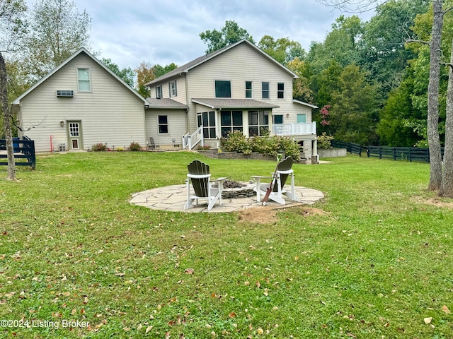 rear view of property featuring a sunroom, a lawn, a patio area, and an outdoor fire pit