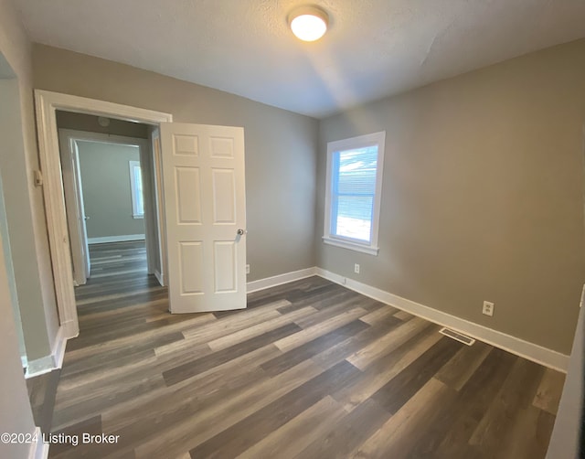 empty room with dark hardwood / wood-style flooring and a textured ceiling