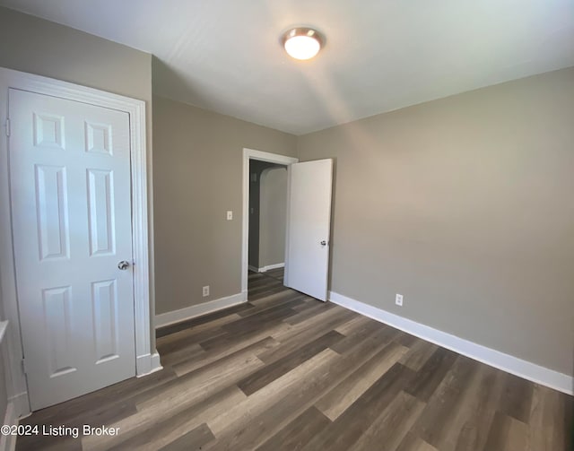 unfurnished bedroom with a closet and dark hardwood / wood-style flooring