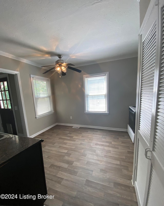 unfurnished dining area featuring ceiling fan, a textured ceiling, dark wood-type flooring, and a wealth of natural light