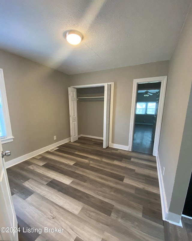 unfurnished bedroom featuring a closet, dark hardwood / wood-style floors, and a textured ceiling