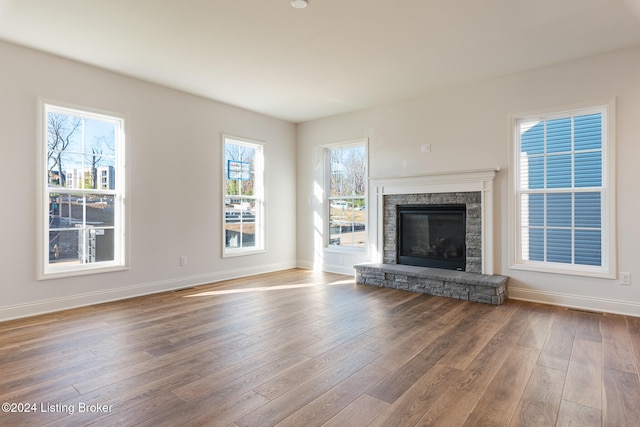 unfurnished living room with a stone fireplace and hardwood / wood-style flooring