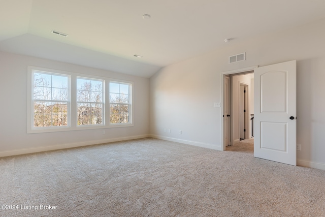 carpeted empty room with lofted ceiling