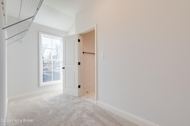 carpeted spare room with lofted ceiling