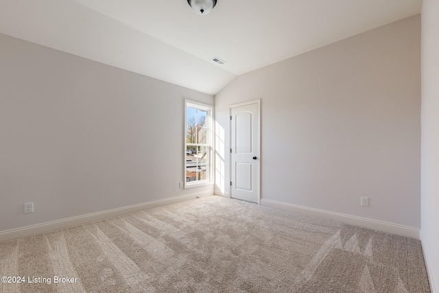 spare room featuring vaulted ceiling and carpet flooring