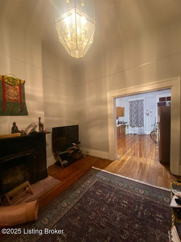 living room with an inviting chandelier, hardwood / wood-style floors, and a high ceiling