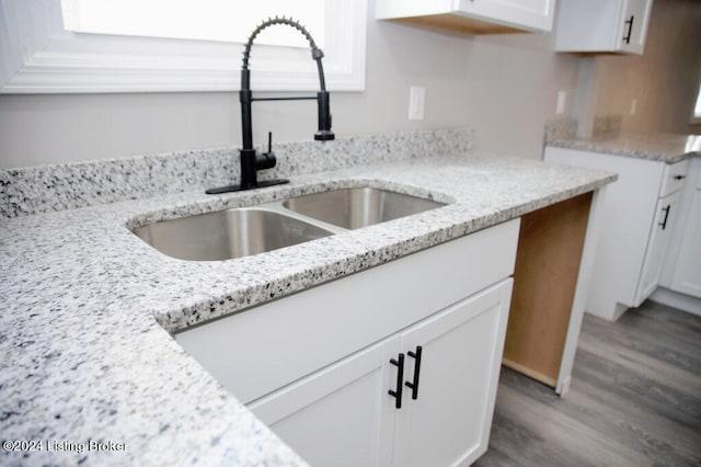 kitchen featuring light stone countertops, white cabinets, sink, and hardwood / wood-style flooring