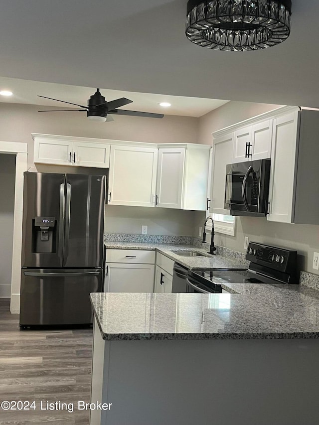 kitchen featuring white cabinets, stainless steel appliances, kitchen peninsula, and stone countertops