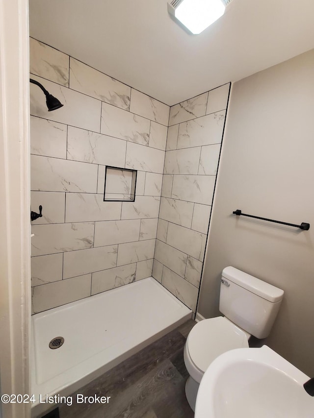 bathroom featuring sink, tiled shower, toilet, and wood-type flooring