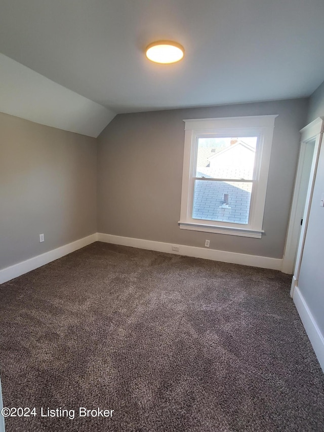 bonus room with lofted ceiling and dark colored carpet