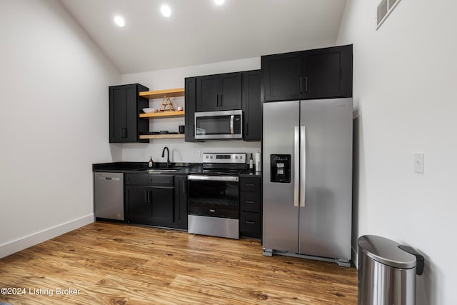 kitchen with sink, vaulted ceiling, stainless steel appliances, and light wood-type flooring