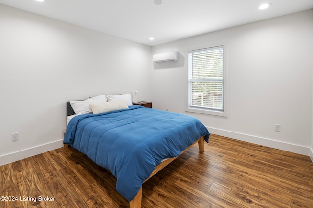 bedroom with a wall unit AC and dark hardwood / wood-style floors