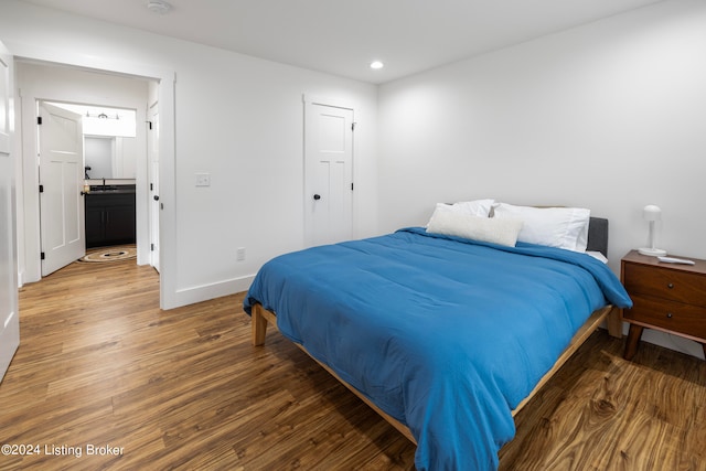 bedroom with ensuite bathroom and dark hardwood / wood-style floors