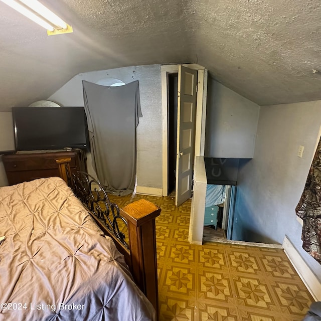 bedroom with vaulted ceiling and a textured ceiling