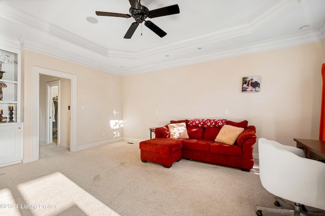 living room featuring light carpet, ornamental molding, a tray ceiling, and ceiling fan