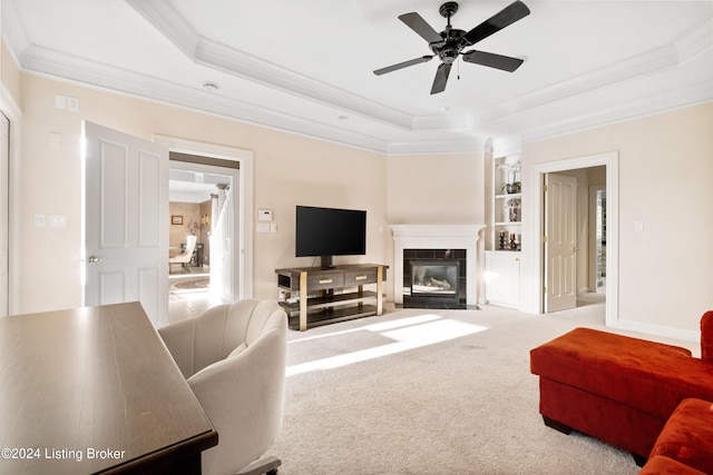 carpeted living room with crown molding, a tray ceiling, and ceiling fan