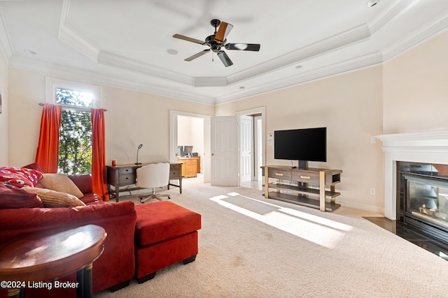 living room with ornamental molding, ceiling fan, carpet, and a raised ceiling