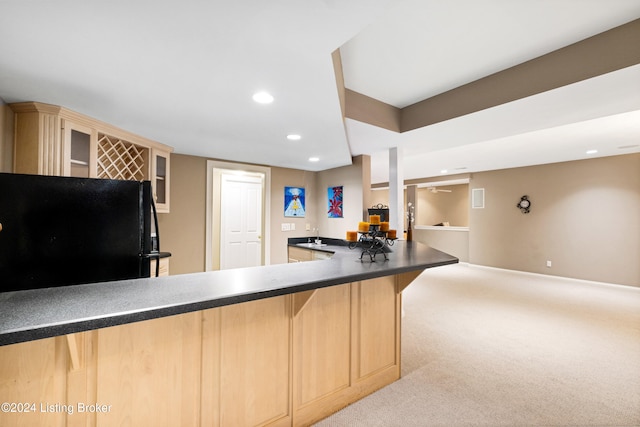 kitchen with light carpet, light brown cabinets, black refrigerator, and a breakfast bar