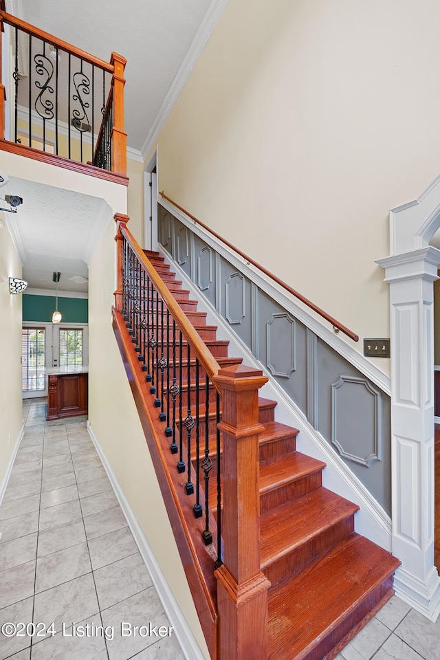 staircase with ornamental molding, tile patterned flooring, and decorative columns