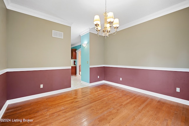 empty room with ornamental molding, light wood-type flooring, and an inviting chandelier