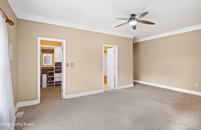 unfurnished bedroom with a spacious closet, ornamental molding, light colored carpet, and ceiling fan