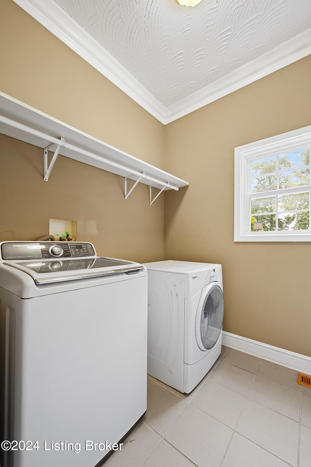 washroom featuring crown molding, washing machine and clothes dryer, light tile patterned floors, and a textured ceiling