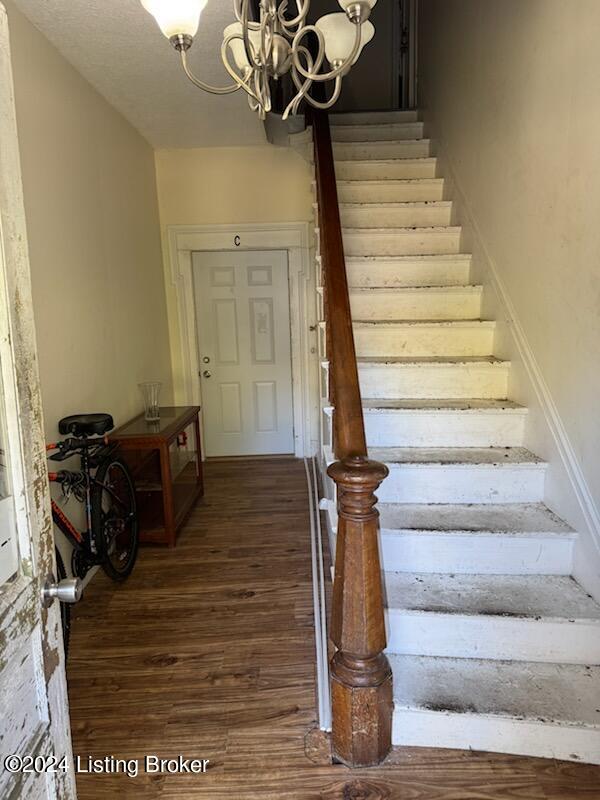 stairway with hardwood / wood-style flooring and a chandelier