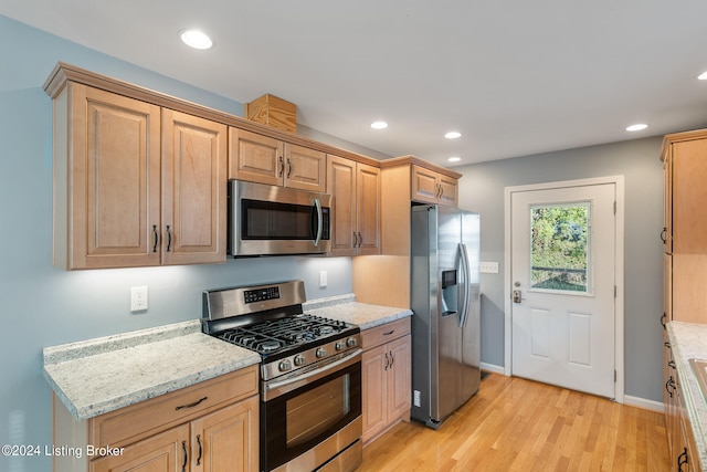 kitchen featuring light stone counters, stainless steel appliances, and light hardwood / wood-style floors