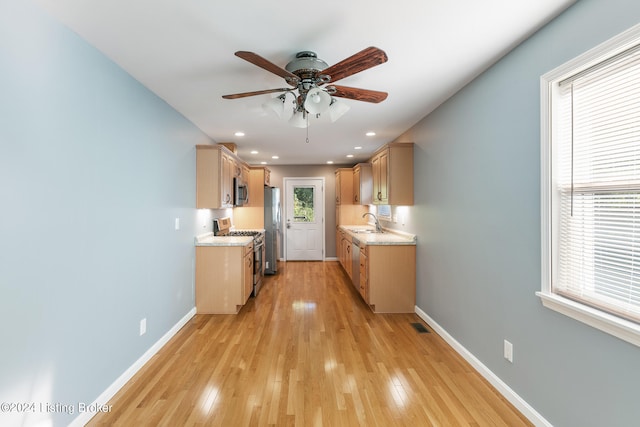 kitchen featuring ceiling fan, light brown cabinetry, light wood-type flooring, sink, and stainless steel appliances