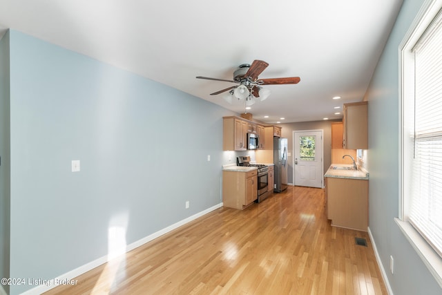 kitchen featuring tasteful backsplash, ceiling fan, sink, light hardwood / wood-style floors, and stainless steel appliances