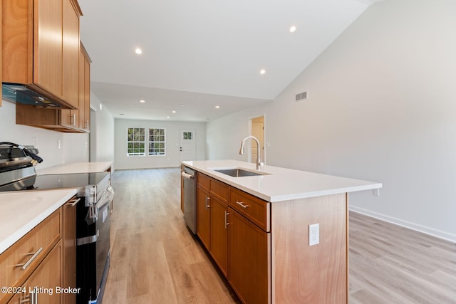 kitchen featuring appliances with stainless steel finishes, sink, light hardwood / wood-style floors, lofted ceiling, and a kitchen island with sink