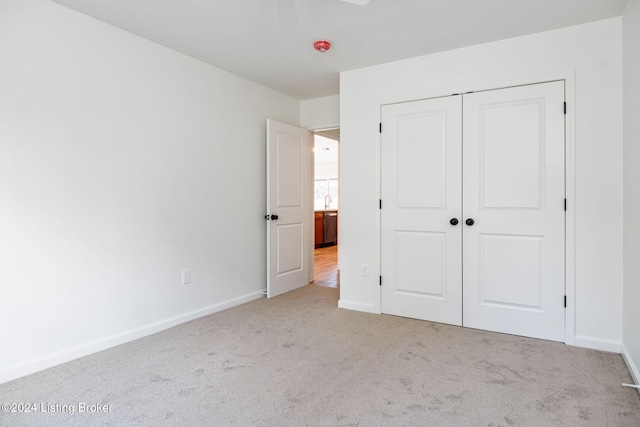 unfurnished bedroom with light colored carpet, ceiling fan, and a closet