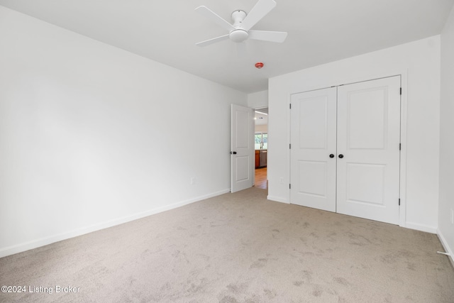 unfurnished bedroom with light carpet, ceiling fan, and a closet