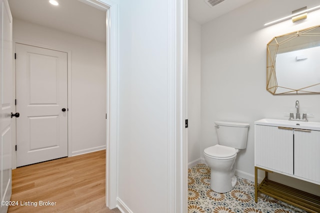 bathroom featuring toilet, vanity, and hardwood / wood-style flooring