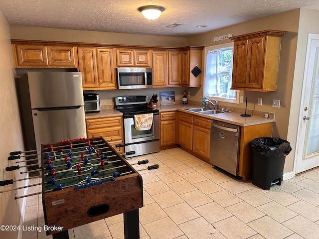 kitchen featuring a textured ceiling, stainless steel appliances, and sink