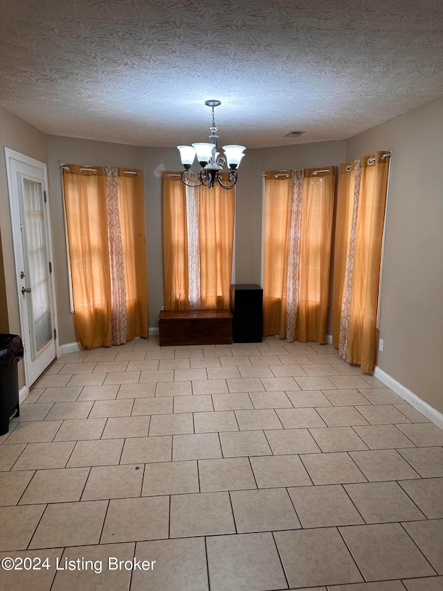 unfurnished dining area featuring a chandelier, light tile patterned floors, and a textured ceiling