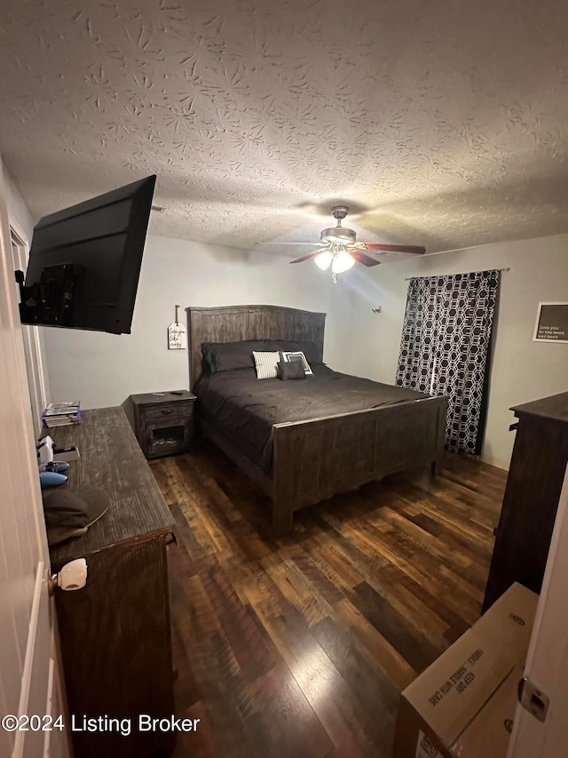 bedroom with ceiling fan, a textured ceiling, and dark hardwood / wood-style floors