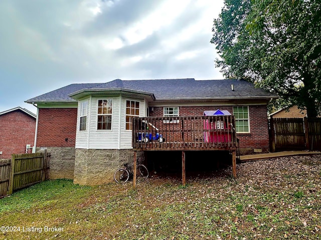 rear view of property featuring a wooden deck and a lawn