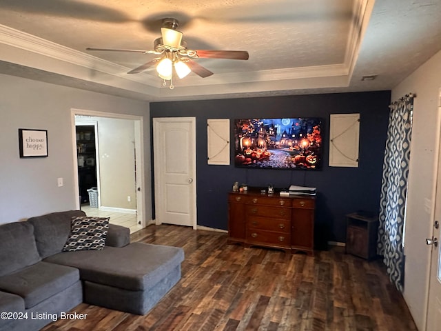 living room with ceiling fan, a raised ceiling, dark hardwood / wood-style flooring, ornamental molding, and a textured ceiling