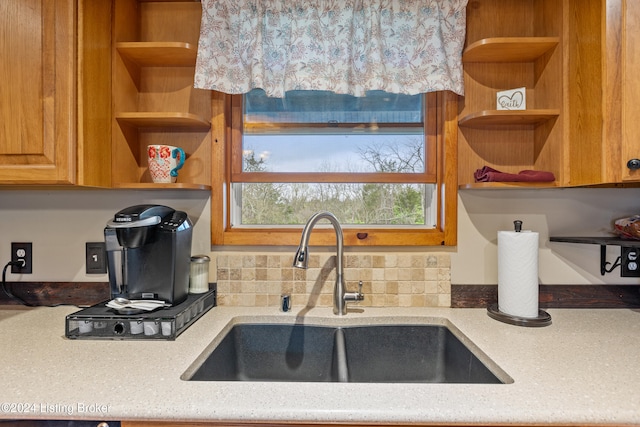 kitchen with light stone counters, sink, and backsplash