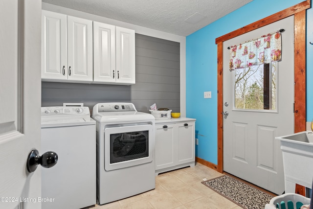 laundry room featuring washer and dryer, cabinets, and a textured ceiling