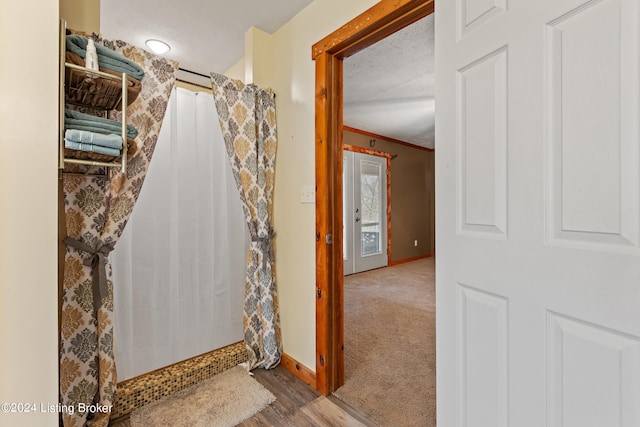 bathroom with curtained shower, wood-type flooring, crown molding, and a textured ceiling