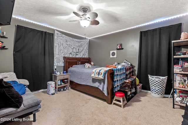 carpeted bedroom featuring ceiling fan and a textured ceiling