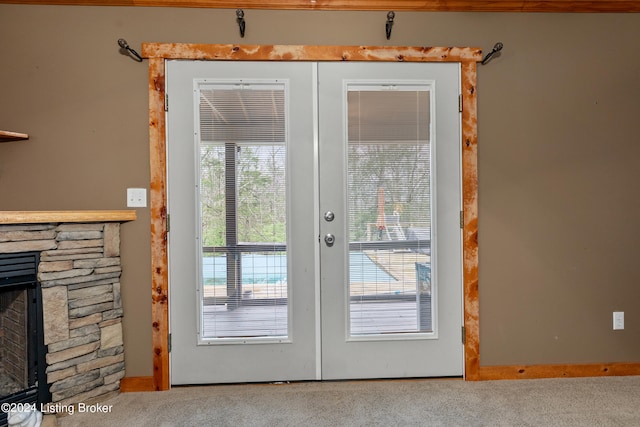 doorway featuring french doors, a stone fireplace, and carpet flooring